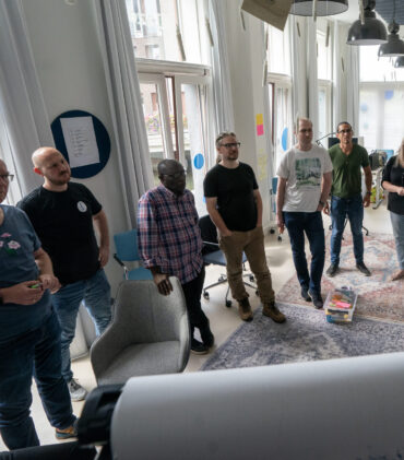 Een groepje medewerkers van TrailBlazers staand rondom een flipover tijdens een TrailBlazers-kwartaalmeeting op 20/8/2024.